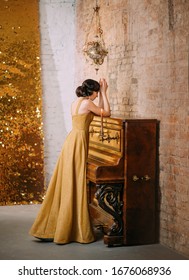 Beautiful sexy sad retro woman near piano hide face pray. finger wave hairstyle. long luxury gold shiny evening dress retro style 30s. Backdrop loft old room bright gloss. stylish outfit graduate prom
