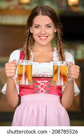 Beautiful, sexy waiter woman holding glasses of beer in a beer pub
