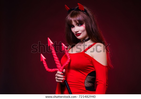 A beautiful, sexy woman in a devil costume, a\
demon with horns and pitchforks, a trident, in a red dress.\
American, dress for a costume party Halloween. Choker on the neck.\
Bright makeup