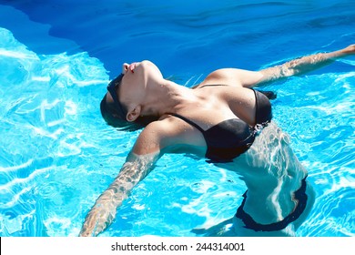 Beautiful Sexy Young Girl With Perfect Slim Figure With Long Wet Hair And Bathing Suit In Fashionable Stylish Sun Glasses Sitting On The Steps Of Swimming Pool Swim, Sunbathe, Have Fun At Beach Party