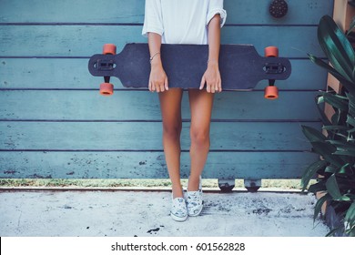 Beautiful sexy young girl in short shorts walking with longboard in sunny weather. Leisure. Healthy lifestyle. Extreme sports. Fashion look, outdoor hipster portrait, Bali, sneakers,hipster,sunset