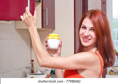 beautiful sexy young woman getting out of the cupboard a jar