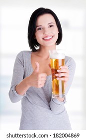 Beautiful and sexy young woman with glass of beer gesturing thumbs up