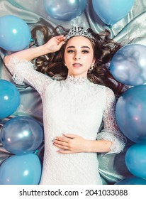 Beautiful Sexy Young Woman In A White Dress And Tiara Lying On The Floor Her Birthday. Top View.