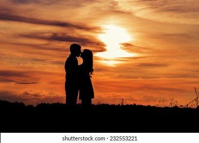 beautiful shade loving happy couple kissing at sunset in a field of warm summer day