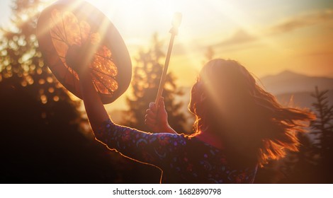 beautiful shamanic girl playing on shaman frame drum in the nature. - Shutterstock ID 1682890798