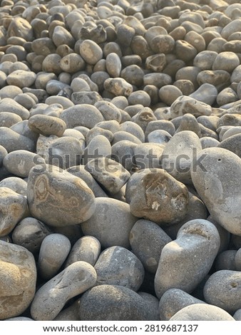 A beautiful, sharp close-up of textured shingle stones on a coastal shore. Clean, natural pattern of rounded river or sea gravel.