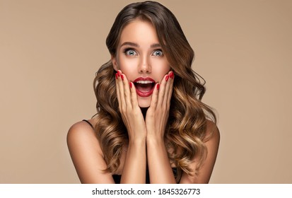 Beautiful Shocked And Surprised Woman Screaming .Beauty Female With Wavy Hairstyle. Curly Hair Girl Amazed . Expressive Facial Expressions . Red Nails Manicure.Beauty , Cosmetic And Makeup