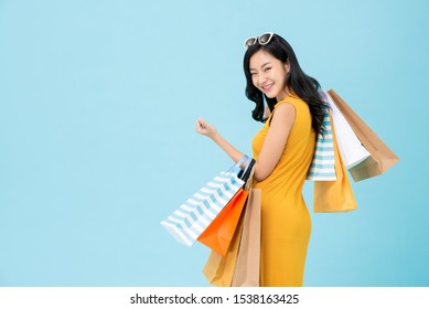 Beautiful Shopaholic Asian Woman Carrying Shopping Bags In Light Blue Background With Copy Space For Sale And Discount Concepts