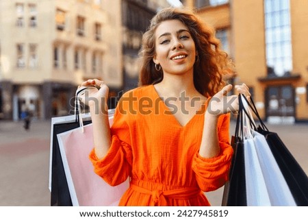 Beautiful Shopping woman with shopping bags walking near the mall. Spring Style. Consumerism, purchases, shopping, lifestyle, sale concept.