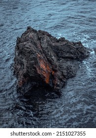 A Beautiful Shot Of A Big Black Rock Formation In The Sea During Daytime