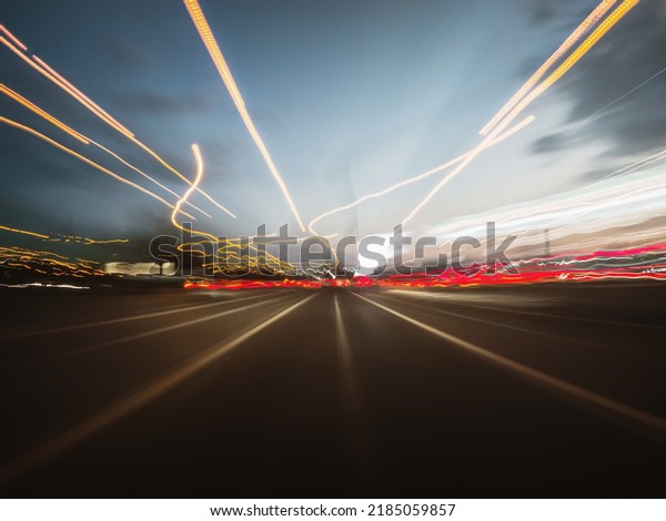 Beautiful shot of a car\
rush on the night road with colorful light trails, front view from\
the car window.