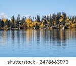 A beautiful shot of colorful autumn trees and cabins on the shore of Grand Lake in Colorado