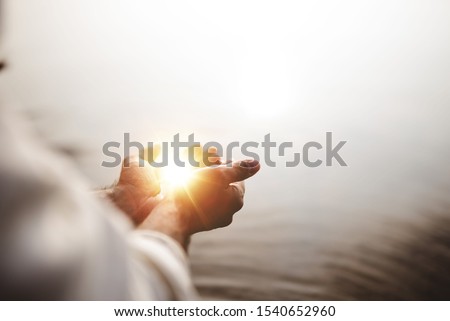 A beautiful shot of Jesus Christ holding hope and light in his palms with a blurred background