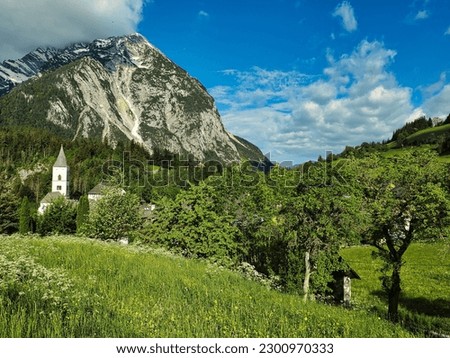 A beautiful shot of the parish church in the small village of Purgg and Grimming peak in Styria, Austria