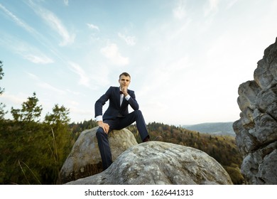 Beautiful shot of romantic wedding couple of groom and bride in gorgeous wedding dress hugging near the big rocks, cliffs in mountains on sunny day. Sunset.Beautiful couple of brides on the rocks.