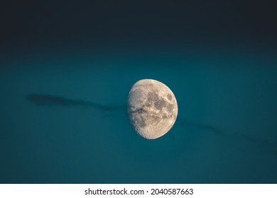 A beautiful shot of a waxing gibbous moon in a dark blue sky with a wispy cloud - Powered by Shutterstock