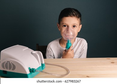 Beautiful Sick Boy Inhalation Therapy By The Mask Of Inhaler. Image Of A Cute Kid With Respiratory Problem Or Asthma. View Of Nebulizer With Smoke From Oxygen Mask.