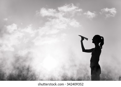 Beautiful Silhouette Of Young Woman Throwing Paper Airplane.