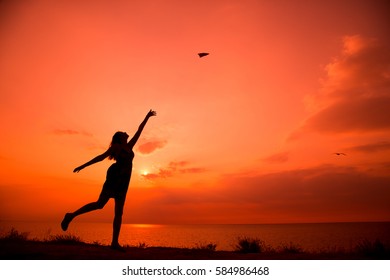 Beautiful Silhouette Of Young Woman Throwing Paper Airplane.