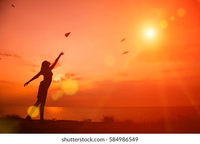 Beautiful Silhouette Of Young Woman Throwing Paper Airplane.