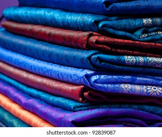 Beautiful silk of different colors and ornament Indian fabric laying in pile
