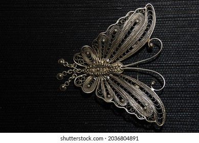A Beautiful Silver Plated Brooch That Is Usually Worn With Traditional Clothes. Butterfly Shape. Jewellery. Isolated.copy Space, Creative, Design. Mock Up, Dark Background 