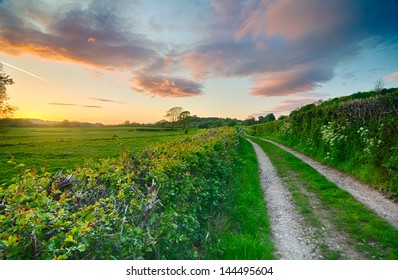 A beautiful sky after sunset on a summer farm track and fields in England, UK with red, orange and pink sky elements