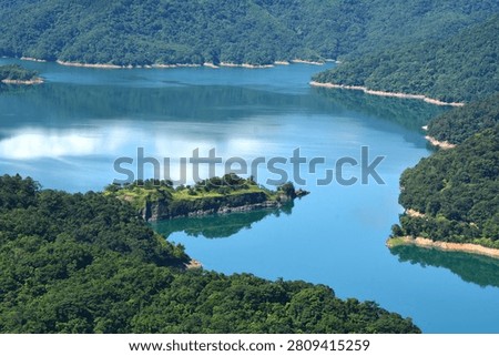 Beautiful sky and cloud reflections on a calm lake surrounded by green mountains