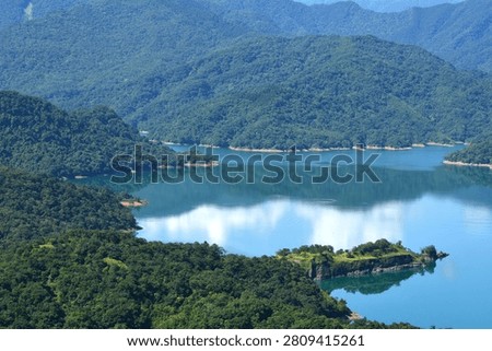 Beautiful sky and cloud reflections on a calm lake surrounded by green mountains