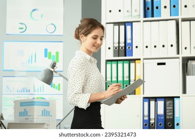 Beautiful slender businesswoman is holding documents in office. Business consultant secretary or manager concept - Shutterstock ID 2395321473