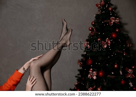 Beautiful slender female legs in pantyhose stockings at christmas tree