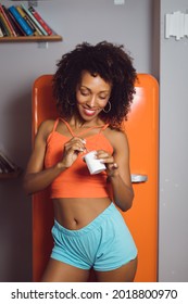 Beautiful Slim Black Woman Eating Yogurt At Home. Fit Afro Hairstyle Female Taking Healthy Snack.