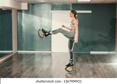 Beautiful slim Caucasian woman in sportswear standing on one leg while wearing kangoo jumps footwear.