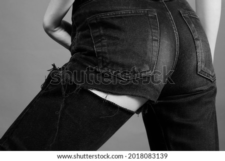 beautiful slim female back in ripped jeans close up, monochrome