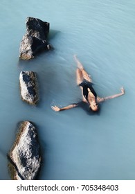 Beautiful Slim Girl With Long Black Hair Relaxing In Blue Lagoon Thermal Bath In Iceland. Natural Spa Treatment