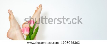 Beautiful slim smooth woman's legs with tulips flowers on white background