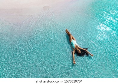 Schöne schlanke Frau, die am Strand in weißem Badeanzug liegt. Aqua Menthe trendige Farbe des neuen Jahres 2020. Konzept der Freizeitinsel-Ferien.