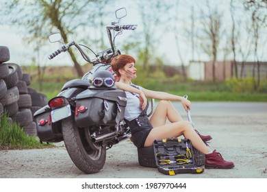 Beautiful Slim Woman Mechanic Sitting Near A Motorcycle