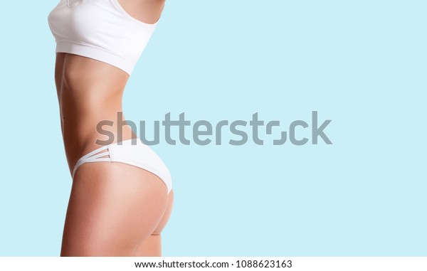 スポーティーな体つきの美しいスリムな女性 青の背景に正常な減量 の写真素材 今すぐ編集