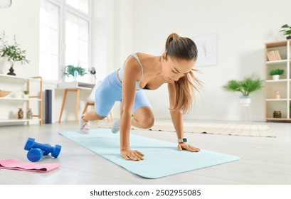 Beautiful slim young Asian woman doing a plank exercise with knee tucks on a yoga mat during her active fitness workout at home. Sport and healthy lifestyle concept - Powered by Shutterstock