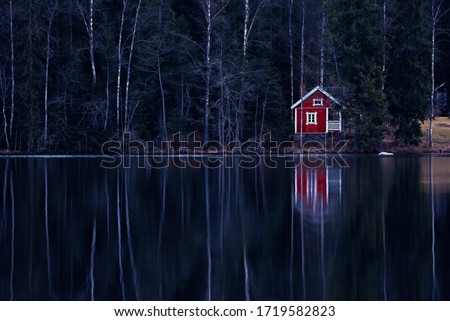 Beautiful small cabin in the beach of the lake in Finnish countryside. Dark, mystical atmosphere.
