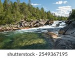 A beautiful small rapids with clear clean water and a blue sky with some clouds in the background, picture from Norway.