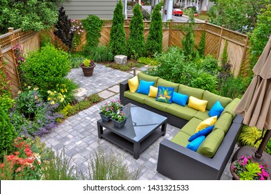 A beautiful small, urban backyard garden featuring a tumbled paver patio, flagstone stepping stones, and a variety of trees, shrubs and perennials add colour and year round interest.