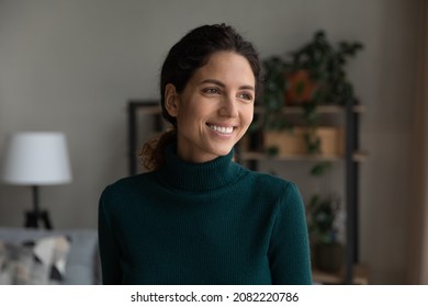 Beautiful smile. Head shot of smiling carefree hispanic female standing at living room looking aside lost in positive optimistic thoughts. Happy young lady enjoying life dreaming visualizing at home - Powered by Shutterstock