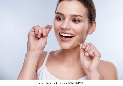 Beautiful Smile, White Strong Teeth. Head And Shoulders Of Woman With Snow-white Smile Holding Tooth Thread, Stomatological Concept. Girl Cleaning Tooth With Thread