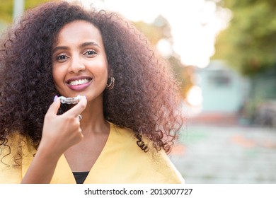 Beautiful smiling African black woman is holding invisaligner. Includes copy and text space.