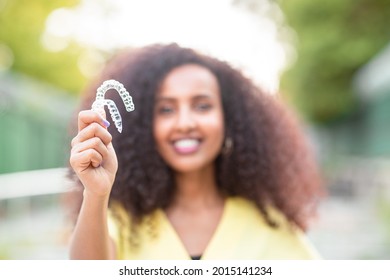 Beautiful smiling African black woman is holding invisaligner. Includes copy and text space.