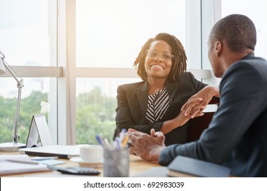 Beautiful smiling African-American business lady chatting with coworker