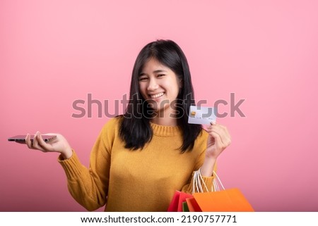 Beautiful smiling Asian girl using her phone and credit card.